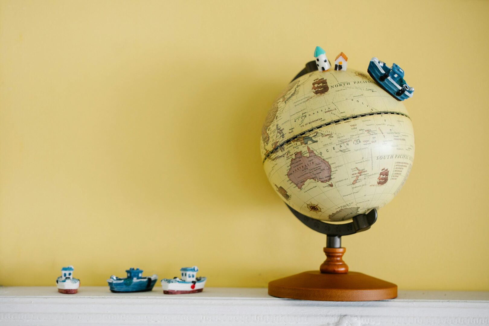 Globe with miniature ships on a yellow background, ideal for travel concepts.